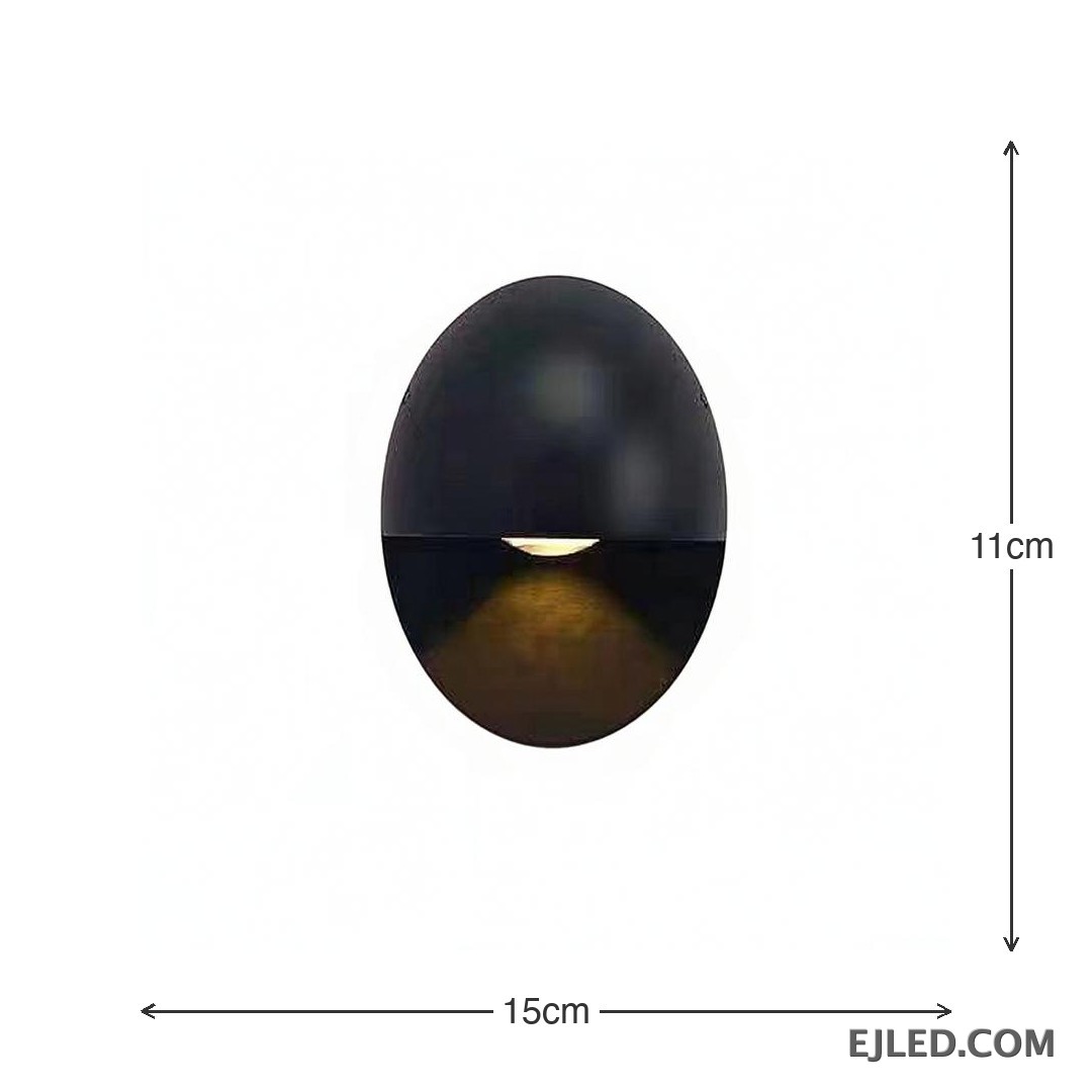 This black oval aluminum wall sconce projects a soft, downward light. Its distinctive design features a concealed light source within the lower half, providing indirect illumination. - view 3