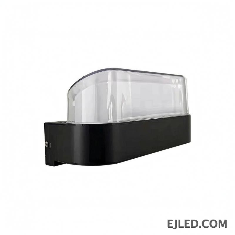 This wall lamp features a rectangular plastic body with a black base and a clear, curved plastic diffuser. It is designed for wall mounting and provides enclosed illumination.