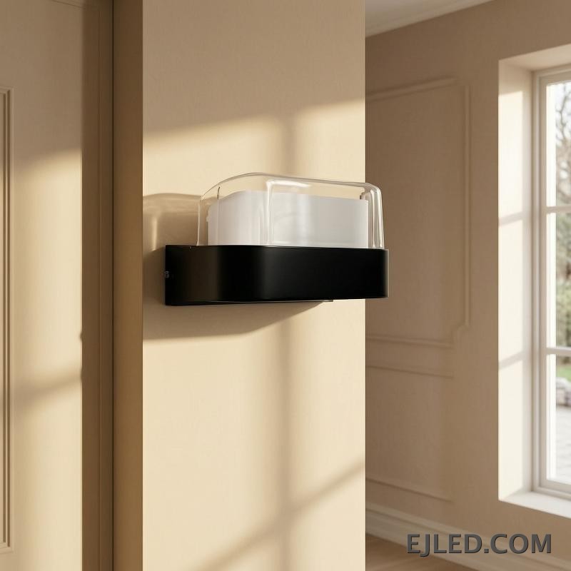 Esta lámpara de pared presenta un cuerpo rectangular de plástico con base negra y un difusor curvo de plástico transparente. Está diseñada para montaje en pared y proporciona iluminación cerrada. - view 5