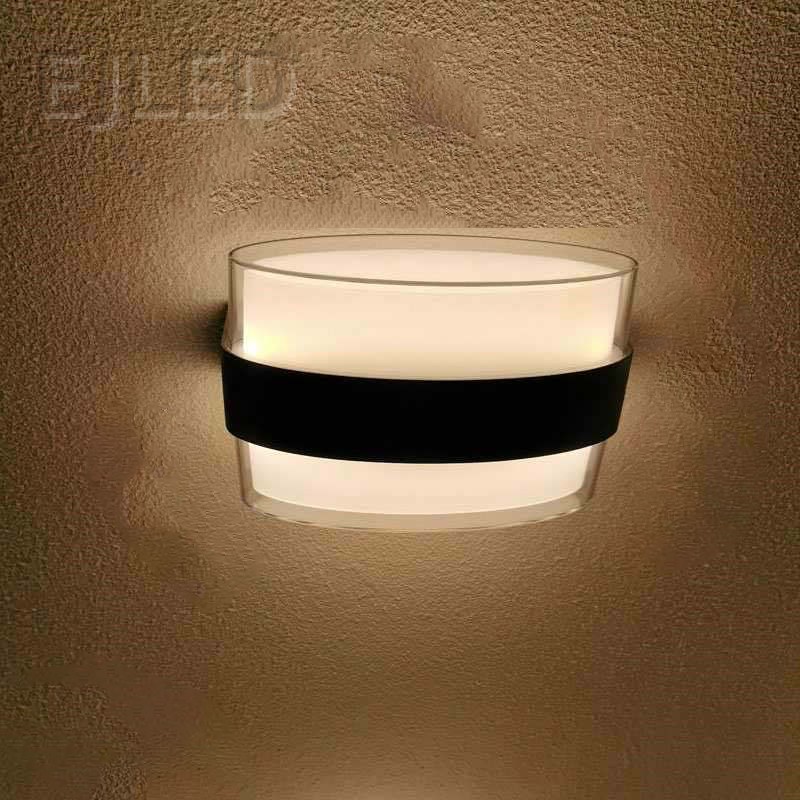 This wall light features a clear acrylic outer layer surrounding a white acrylic diffuser. A distinctive black band wraps around the middle, providing a modern and clean aesthetic for various interior settings. - view 2