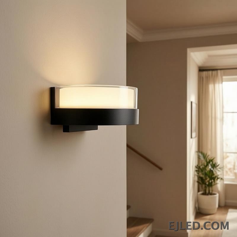This round light fixture features a clear glass cylinder encasing a diffused white light, set upon a dark, circular base. It measures 185x80x85MM. - view 4