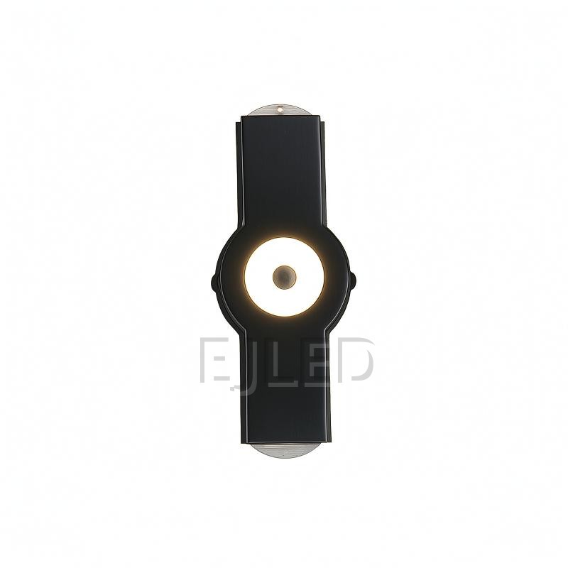 Este aplique de pared de aluminio negro presenta un cuerpo rectangular con un elemento circular luminoso central y extremos de montaje expuestos, creando una silueta moderna distintiva.