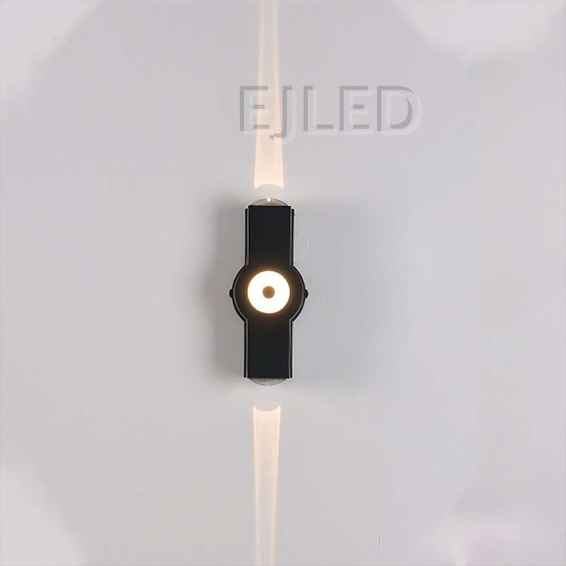 Este aplique de pared de aluminio negro presenta un cuerpo rectangular con un elemento circular luminoso central y extremos de montaje expuestos, creando una silueta moderna distintiva. - view 2