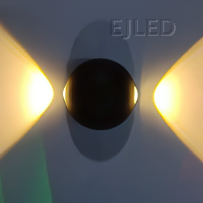 This wall light features a round black acrylic body flanked by two glowing triangular shades that project warm light outward on both sides. - view 2