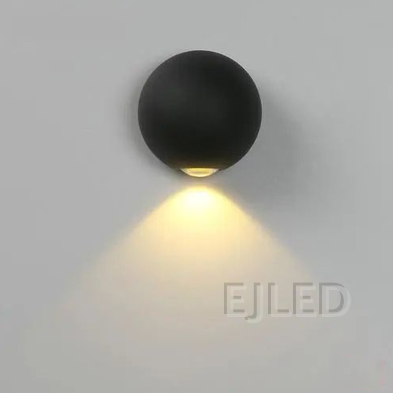 This wall light features a round black acrylic body flanked by two glowing triangular shades that project warm light outward on both sides. - view 3