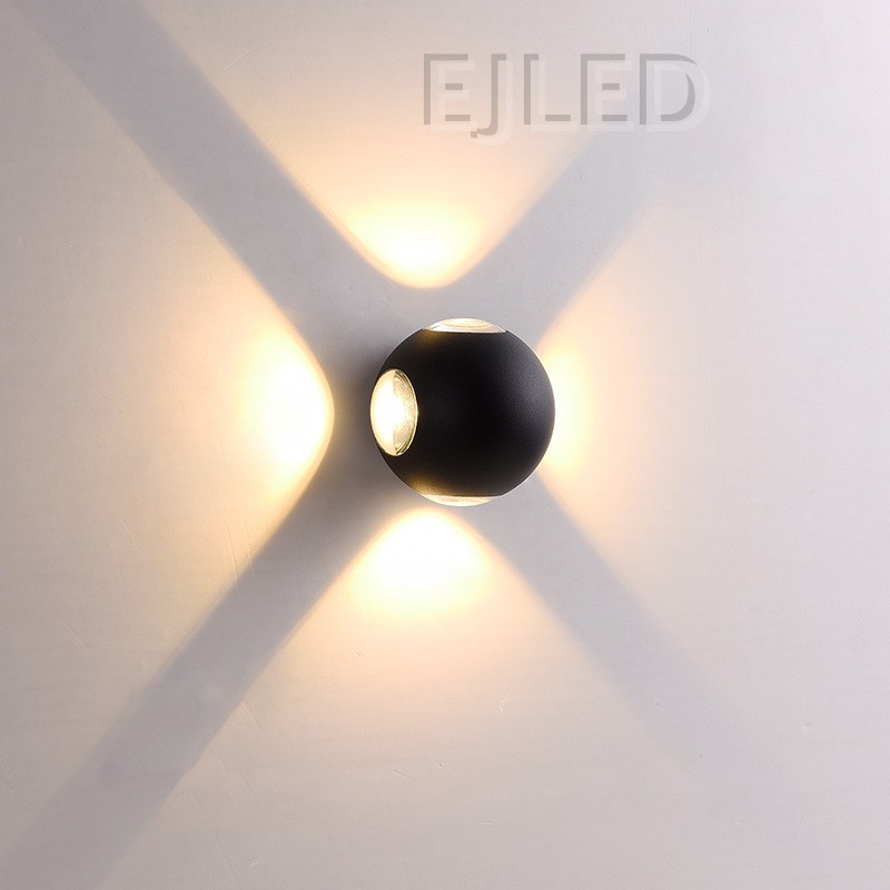 This wall light features a round black acrylic body flanked by two glowing triangular shades that project warm light outward on both sides. - view 5