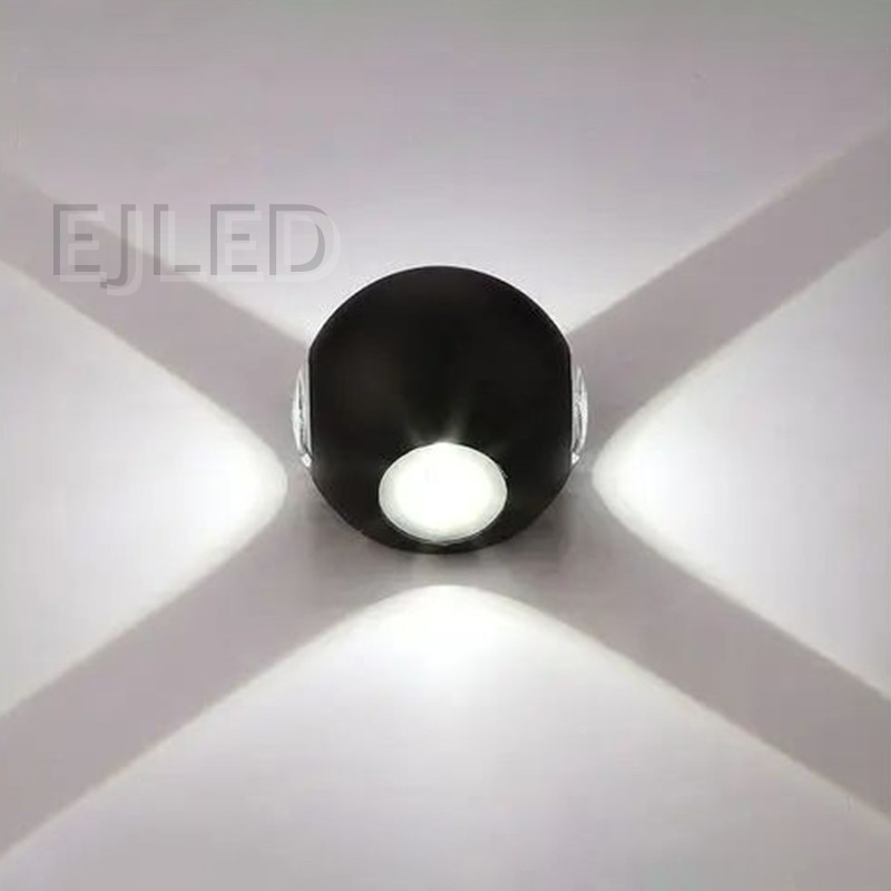 This wall light features a round black acrylic body flanked by two glowing triangular shades that project warm light outward on both sides. - view 6