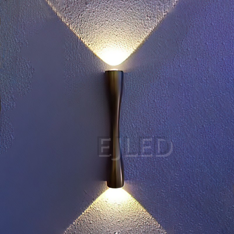 This black brass wall light features a slender cylindrical metal body with a distinct hourglass contour, designed for targeted directional illumination in hospitality and residential projects. - view 2