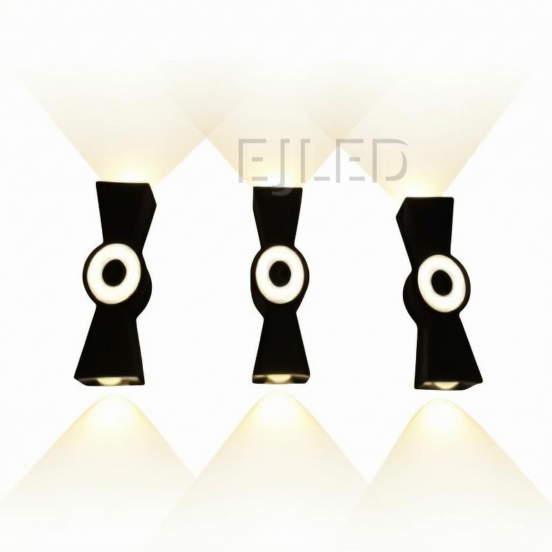 This black plastic wall light features a dual-directional beam design with integrated circular light elements and open top and bottom openings.