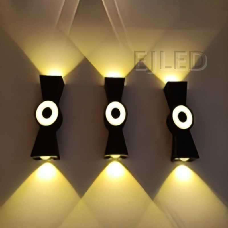 This black plastic wall light features a dual-directional beam design with integrated circular light elements and open top and bottom openings. - view 2